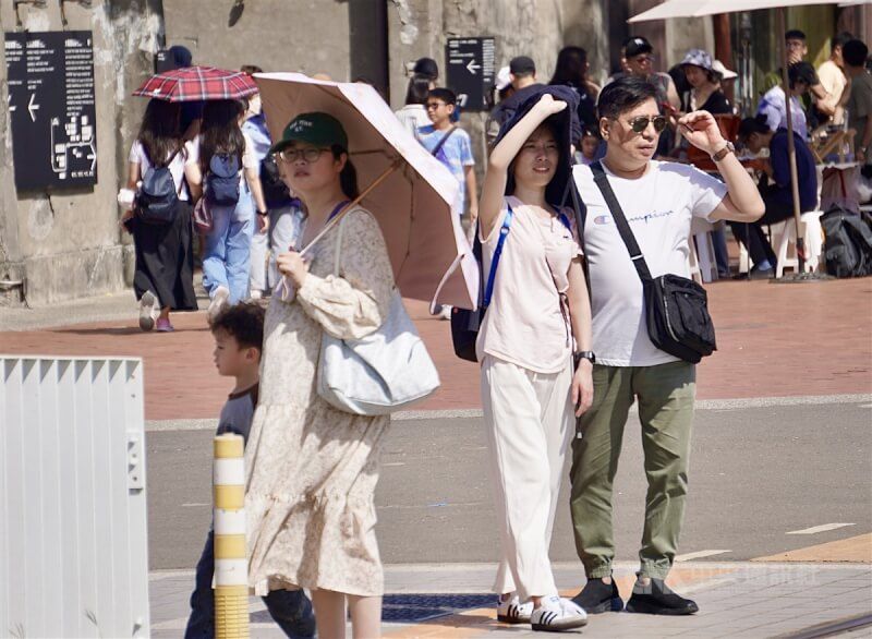 圖為高雄市鹽埕區出遊民眾，有人撐傘、拿起薄外套遮陽。（中央社檔案照片）